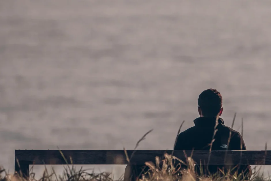 A man sits alone on a bench overlooking the sea, capturing a serene moment in A Coruña, Spain.
